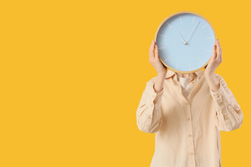 Woman with wall clock on yellow background
