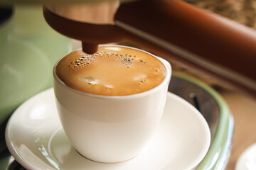 Coffee machine with cup of espresso on table in kitchen, closeup