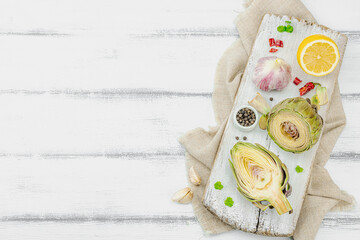 Fresh green artichokes cooking on wooden background. Traditional seasonal ingredients