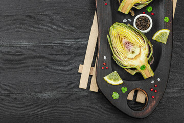 Fresh green artichokes cooking on wooden background. Traditional seasonal ingredients