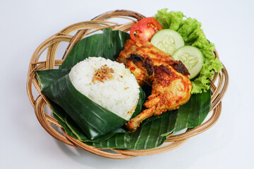 Roasted chicken with soy sauce, herbs and spice from Indonesia. Ayam bakar kecap served with cucumber and chili sauce. White plate