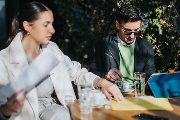 A professional young team engages in a creative meeting in a relaxing outdoor setting, working together over discussions and documents.
