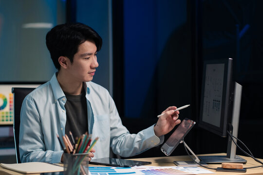 Male coder or developer working overtime using a computer display in problem solving at workplace.