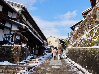 観光名所中山道の馬籠宿の古い町並みの雪景色と観光客の姿