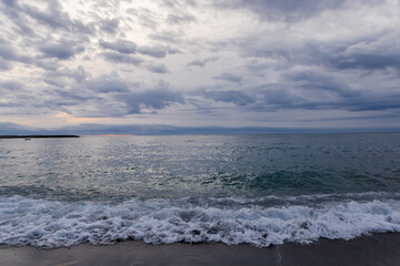 Sea surf waves on a sandy shore in overcast morning