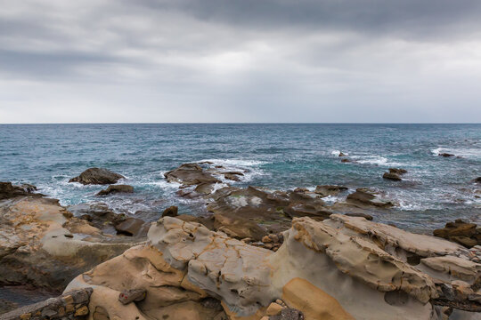 Fototapeta Sea surf waves between coastal rocks in overcast rainy weather