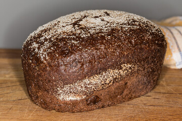 Brown bread on wooden cutting board, front view close-up