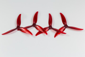 Trilobate red plastic propellers for FPV drone on gray background