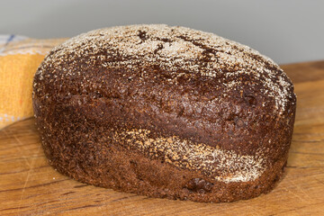 Whole brown bread on a wooden surface close-up
