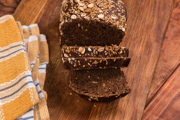 Partially sliced grain brown bread on cutting board, top view
