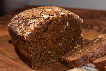 Partially sliced grain brown bread, close-up in selective focus