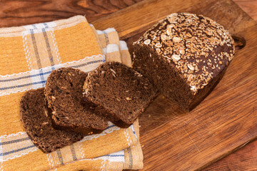 Partially sliced grain brown bread on cutting board, top view