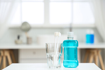 Holder of toothbrushes with mouth rinse on table in bathroom