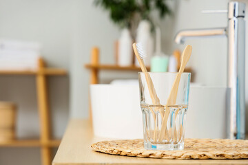Holder of toothbrushes near sink on table in bathroom