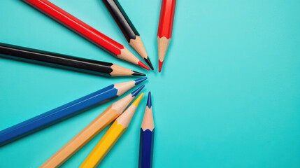 Naklejka premium Colorful pencils arranged in circular pattern on turquoise background create vibrant and artistic display