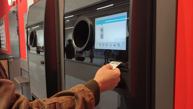 Warsaw, Poland - May 31, 2025: Close up of man hand getting coupon from recycling machine for inserted bottles