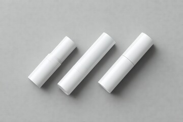 Three blank white cylindrical cosmetic containers of varying heights arranged diagonally on a neutral gray background