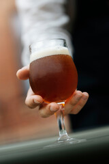 A hand holding a glass full of beer