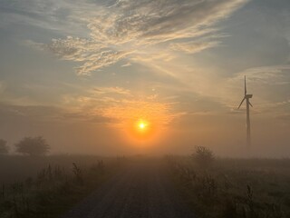 sunrise over the road with wind turbine in the morning fog