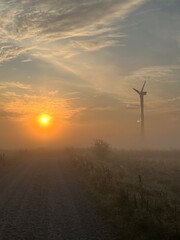 Obraz premium wind turbine in the field in the sunrise a foggy morning