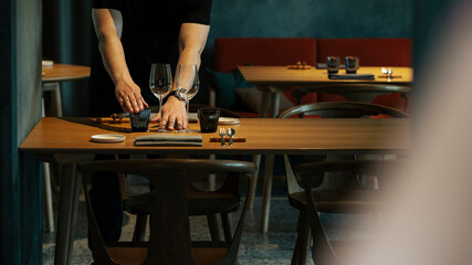 A man arranges the restaurant table setting, ready to welcome guests.