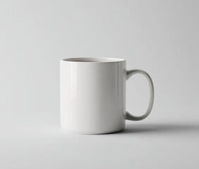 Obraz premium A simple, cylindrical white mug sits on a light grey surface, casting a subtle shadow. It's filled with a dark liquid, possibly tea or coffee