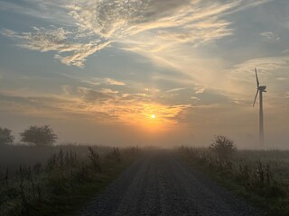 wind turbine in the field in the sunrise a foggy morning