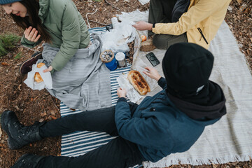 A group of friends gathers on a picnic blanket in a forest, sharing snacks and engaging in...