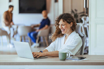 Smiling Professional Woman Working At Desk In Modern Office Environment