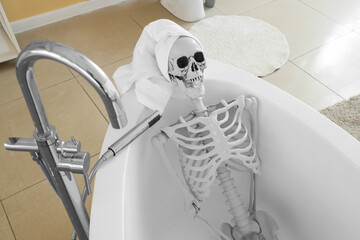 Skeleton with towel lying in bathtub at home