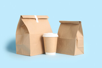 Paper bags with coffee cup on blue background. Food delivery service
