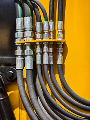 Detailed view of hydraulic hoses and connectors in heavy machinery at a construction site during daytime