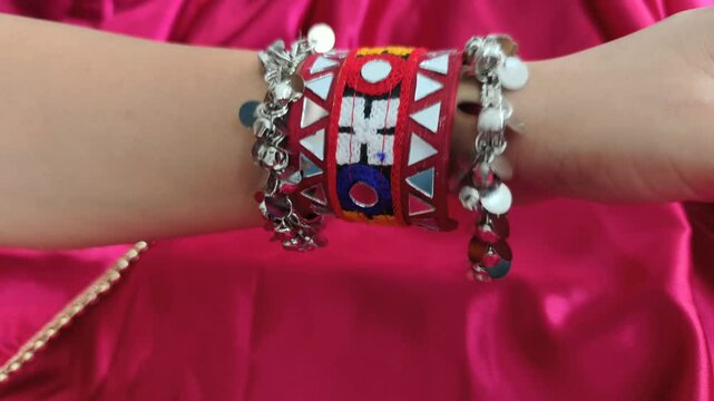Close-up of a vibrant embroidered ethnic bracelet with mirror work paired with oxidized coin and ghunghroo bangles for Navratri festival while playing garba and dandiya. 