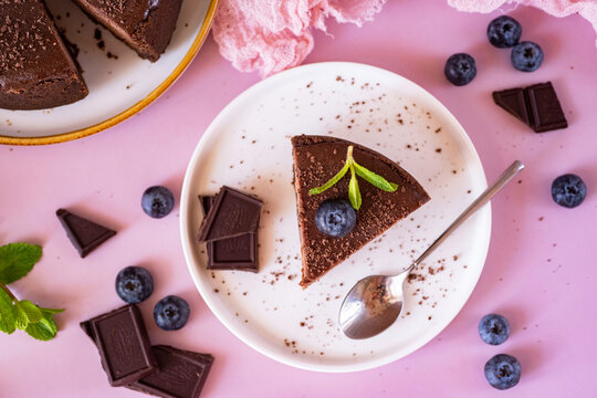 Sweet breakfast: a piece of chocolate cheesecake on a white plate on a pink background. Chocolate cheesecake for dessert. View from above. Close-up