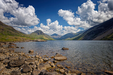 a Rocky shore with blue sky and fluffy white clouds over Wastwater in Wasdale The Lake District of...