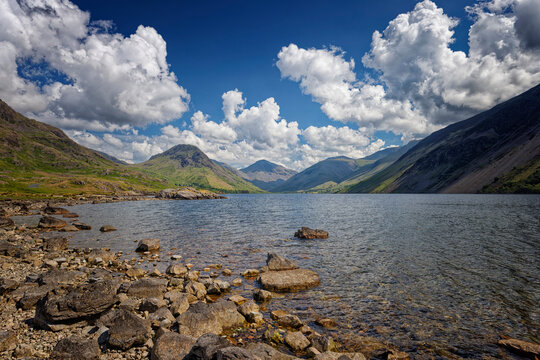 a Rocky shore with blue sky and fluffy white clouds over Wastwater in Wasdale The Lake District of Cumbria UK