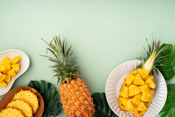 Fresh pineapple chunks served in a pineapple bowl on green table background.