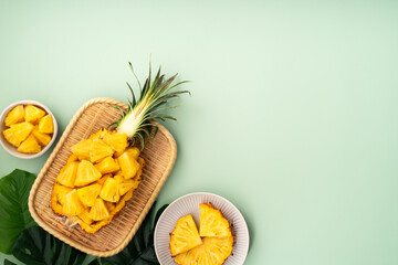Fresh pineapple chunks served in a pineapple bowl on green table background.