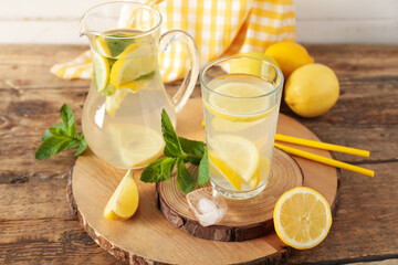 Fototapeta premium Glass and jug of fresh lemonade with mint on wooden table, closeup