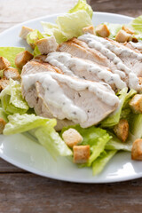 Crunchy Caesar salad with chicken on wooden table