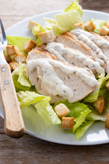 Crunchy Caesar salad with chicken on wooden table
