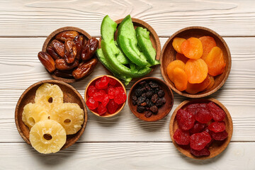 Bowls with different candied fruits on white wooden background