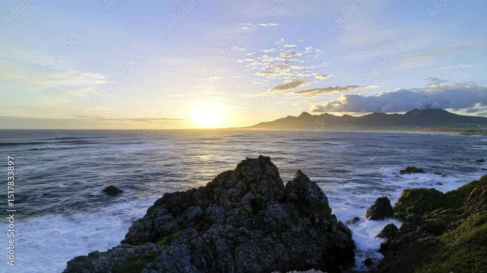 Poster waves crash against rocky cliffs as the sun rises over the ocean with distant mountains under a part