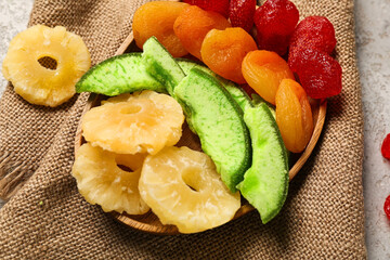 Wooden plate with different candied fruits on grey background, closeup