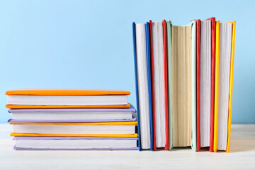 Many colorful books on white wooden against blue background
