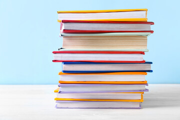 Stack of colorful books on white wooden table against blue background