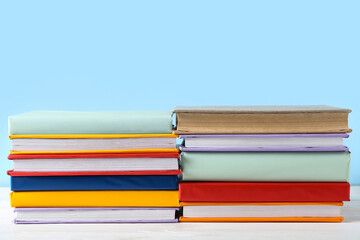 Stacks of colorful books on white wooden table against blue background