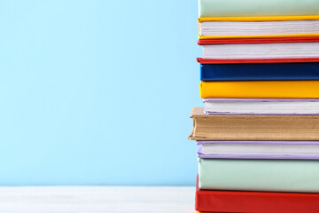 Stack of colorful books on white wooden table against blue background