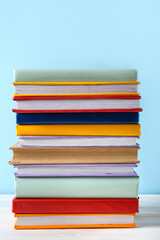 Stack of colorful books on white wooden table against blue background