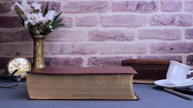 Bible falling for study on gray table with glasses clock and coffee in the morning. Preparation for communion and worship concept. Slow motion
